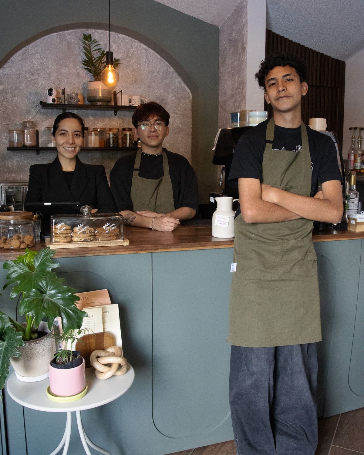 Drie medewerkers van een kleine zaak staan samen achter de toonbank